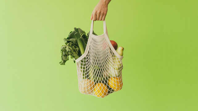 A product photography shot of a white mesh string bag against a solid lime green background.