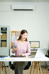 Asian designer using digital pen and laptop in a creative office, showcasing professional work,...