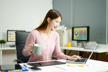Happy creative designer works with coffee and laptop in modern office, showcasing productivity,...