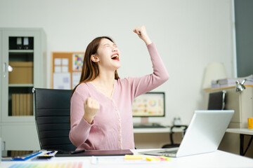 Joyful designer celebrates achievement while using tablet in modern workspace, showcasing...