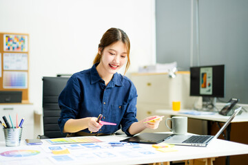 Creative designer stands at her workspace, planning UX/UI with color swatches and wireframes