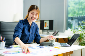 Creative designer stands at her workspace, planning UX/UI with color swatches and wireframes