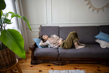 Leisurely woman lying in relaxed pose, daydreaming while enjoying peaceful isolation alone at home....