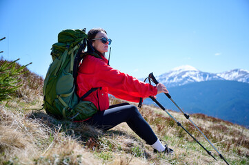 Female hiker with backpack and trekking poles walking in the mountains. Adventure lifestyle in...