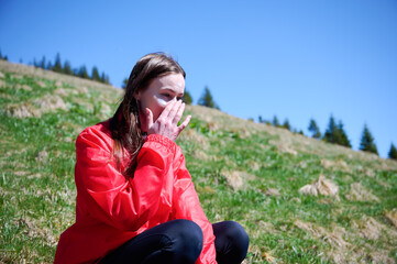 Woman hiker applying sunscreen while sitting on the hill in the mountains. Female in the mountains...