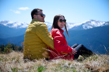 Two hikers taking a break on a mountain ridge. Sporty couple with hiking backpacks standing on...