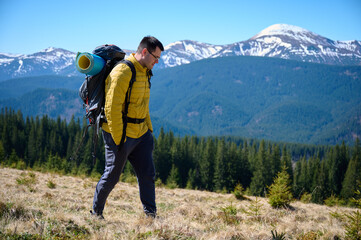 Two hikers taking a break on a mountain ridge. Sporty couple with hiking backpacks standing on...