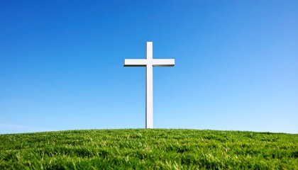 White cross on grassy hill under a clear blue sky
