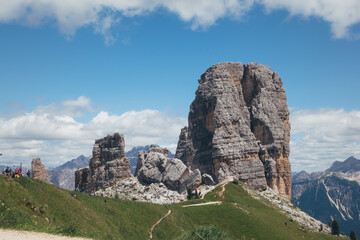 Majestic rock formations and lush green landscape of the Dolomites mountains under a clear blue sky.