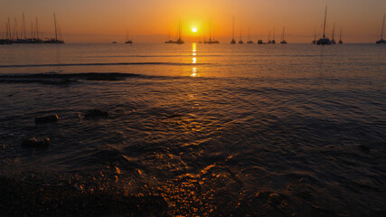 Serene Sunset Over Calm Sea with Sailboats