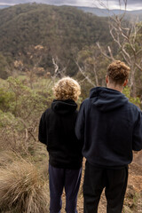 Two brothers admiring scenic view of green forest on winter road trip