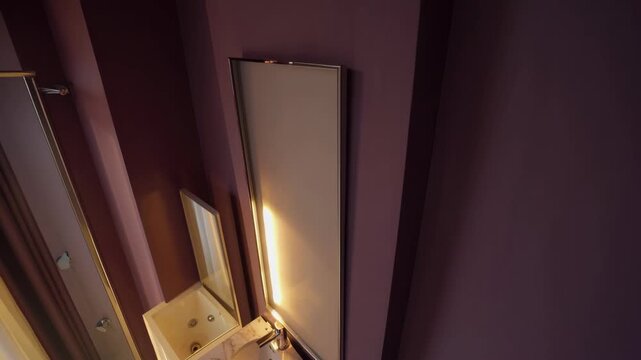 Elegant purple bathroom with three mirrors, radiating a sense of sophistication. The image is taken from a unique perspective, highlighting the luxurious decor.