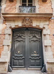 Large ornate door on residential building in Paris, France.