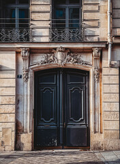Large ornate door on residential building in Paris, France.