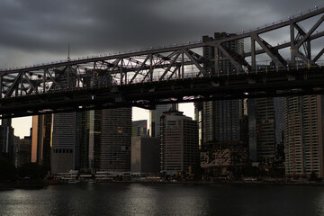 Steel bridge spanning over river with modern skyscrapers, Brisbane