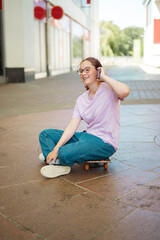 Teen age girl talking on smartphone, sitting on skateboard