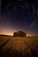 Circumpolar of stars over a pile of hay bales