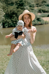 Smiling mother holds baby girl in matching polka dot dresses