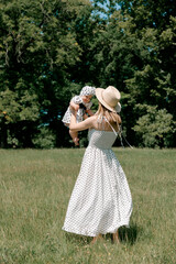 Mother lifting baby in meadow on sunny summer day