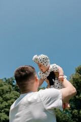 Father holding smiling baby girl under summer sky