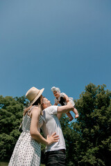 Parents lifting baby girl on sunny summer day