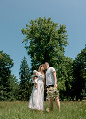 Parents kissing while holding baby and flowers