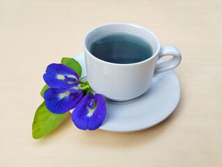 Boiled butterfly pea flower water in a glass on wooden table background. Healthy herbal drink	