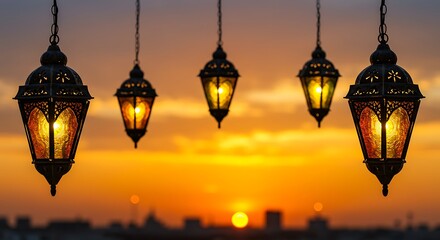 Obraz premium Five ornate lanterns hang illuminated against a vibrant sunset sky, casting a warm glow.