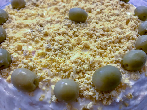 Russian salad presented on a ceramic plate and decorated with olives