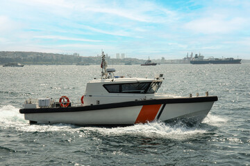 A sleek boat glides swiftly past a distant city skyline