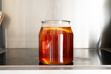 Fermenting kombucha in glass jar on kitchen counter