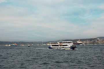 Several boats are cruising across the calm water at twilight
