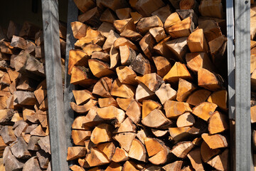 Stacked firewood logs in sunlight showing natural wood texture and grain variations