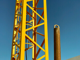 metal structure of a metallic construction site jib crane and the blue sky in the background