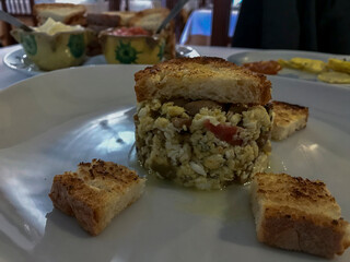 plate of mushroom scrambled eggs with slices of toasted bread, on a white plate at a restaurant table