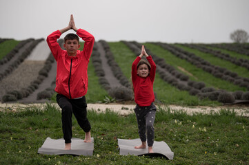 Two children practice yoga in a serene lavender field, connecting with nature as they embrace...