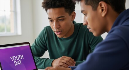 Two young men looking at laptop screen with "youth day" text. International Youth Day celebration and awareness concept.