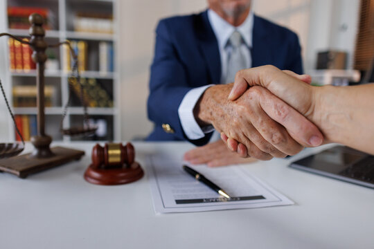 Happy mid aged business lawyer man manager handshaking greeting client in office. Smiling female executive making successful deal with partner shaking hand at work standing at meeting table.
 - Powered by Adobe