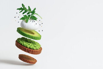 Deconstructed avocado toast with floating layers includes bread, mashed avocado, sliced avocado, mozzarella, arugula, and sesame seeds, creating fresh and artistic presentation with copy space