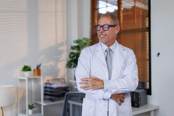 Healthcare, medical staff concept. Portrait of smiling male doctor posing with folded arms on free...