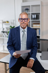 Mid shot of happy middle aged business man or lawyer male ceo standing in office arms crossed....
