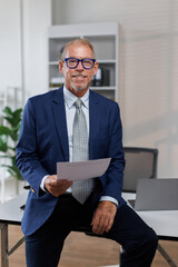 Mid shot of happy middle aged business man or lawyer male ceo standing in office arms crossed....