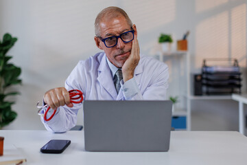 Worried male doctor working on computer at he desk.doctor, worried,stress, tired, laptop, black,...