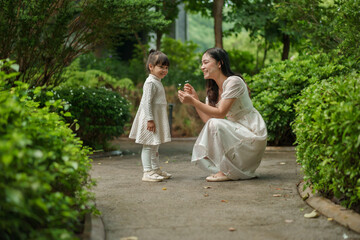 happy mother and toddler girl with Ruellia simplex or Mexican petunia flower in garden
