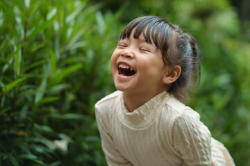 cheerful toddle girl in white dress laughing in the garden