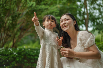 happy mother and toddler girl with Ruellia simplex or Mexican petunia flower in garden