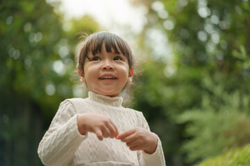 portrait of happy smiling toddler girl in white dress with nature background
