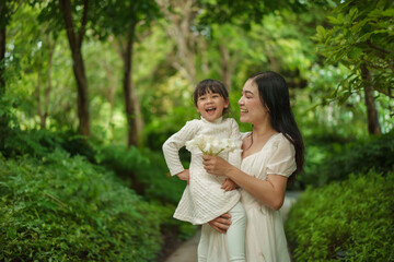 happy mother holding and talking with toddler girl in garden