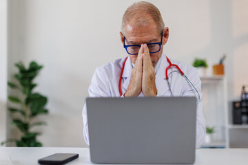 Worried male doctor working on computer at he desk.doctor, worried,stress, tired, laptop, black, computer, nurse, pain, headache, Modern medicine and healthcare concept
