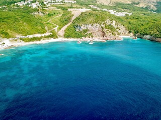A drone photo of the coastline of Sveti Stefan with beautiful bright colors in the sea in Montenegro